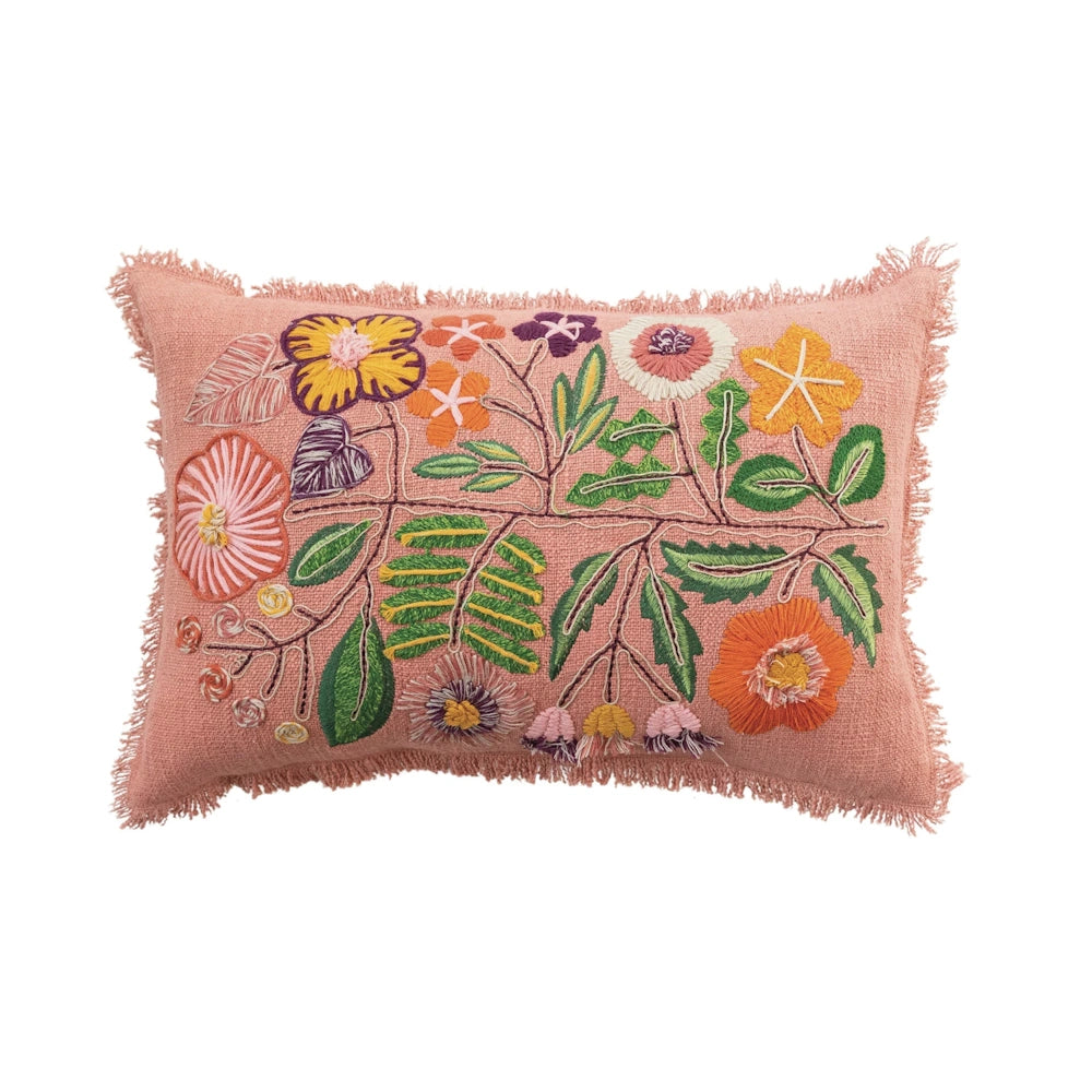 Pink lumbar pillow with colorful floral embroidery and fringe trim on a white background.