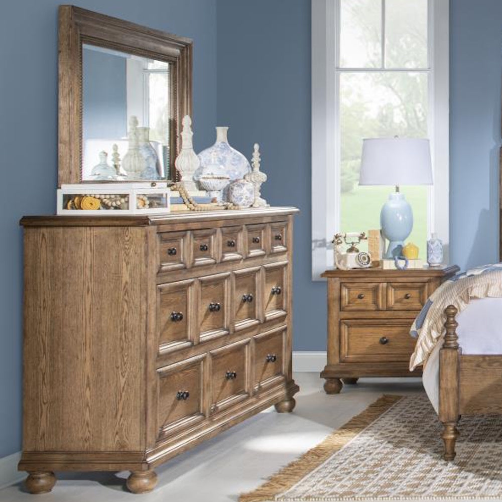 Rustic wood dresser with mirror in a blue bedroom beside a matching nightstand and bed.