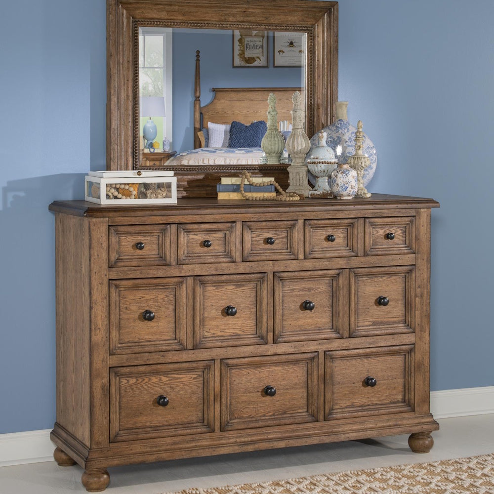 Rustic wood dresser with eight paneled drawers, topped with decor and a matching framed mirror.