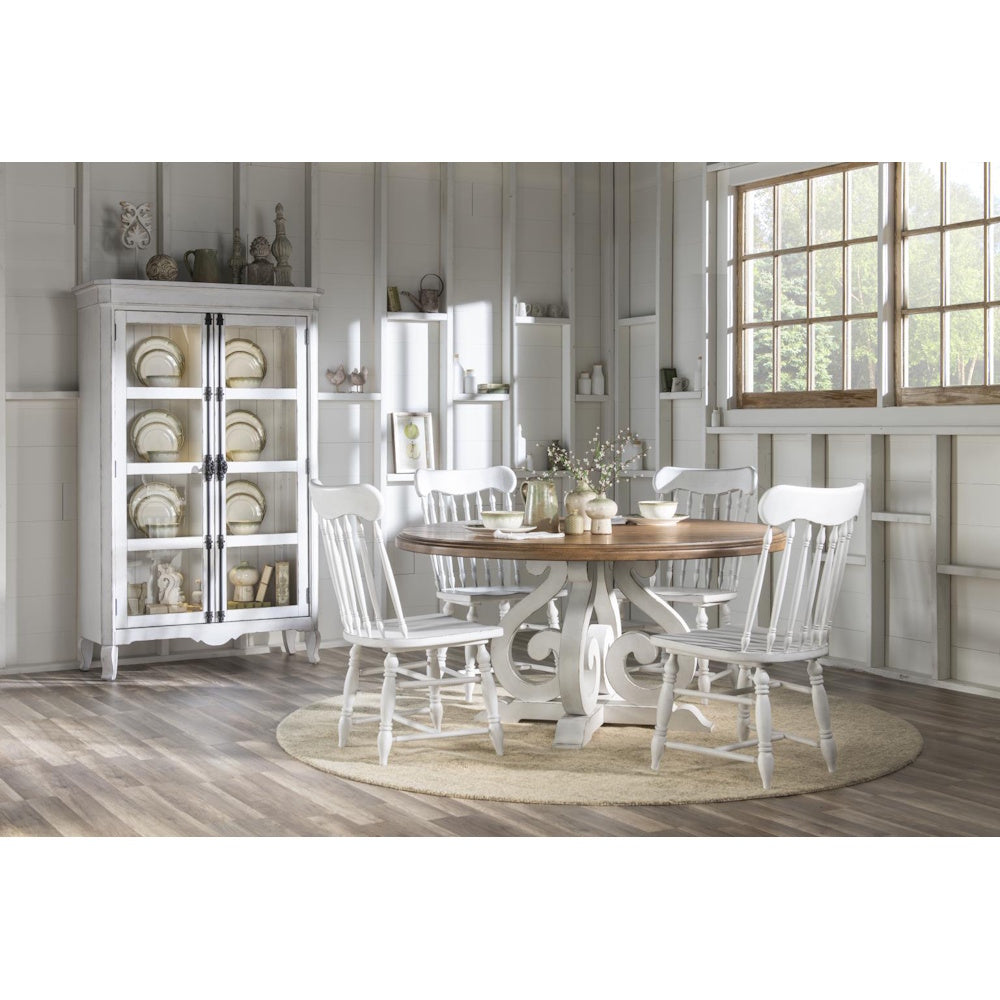 Rustic white farmhouse dining set with round wood table, spindle chairs, and glass display cabinet.