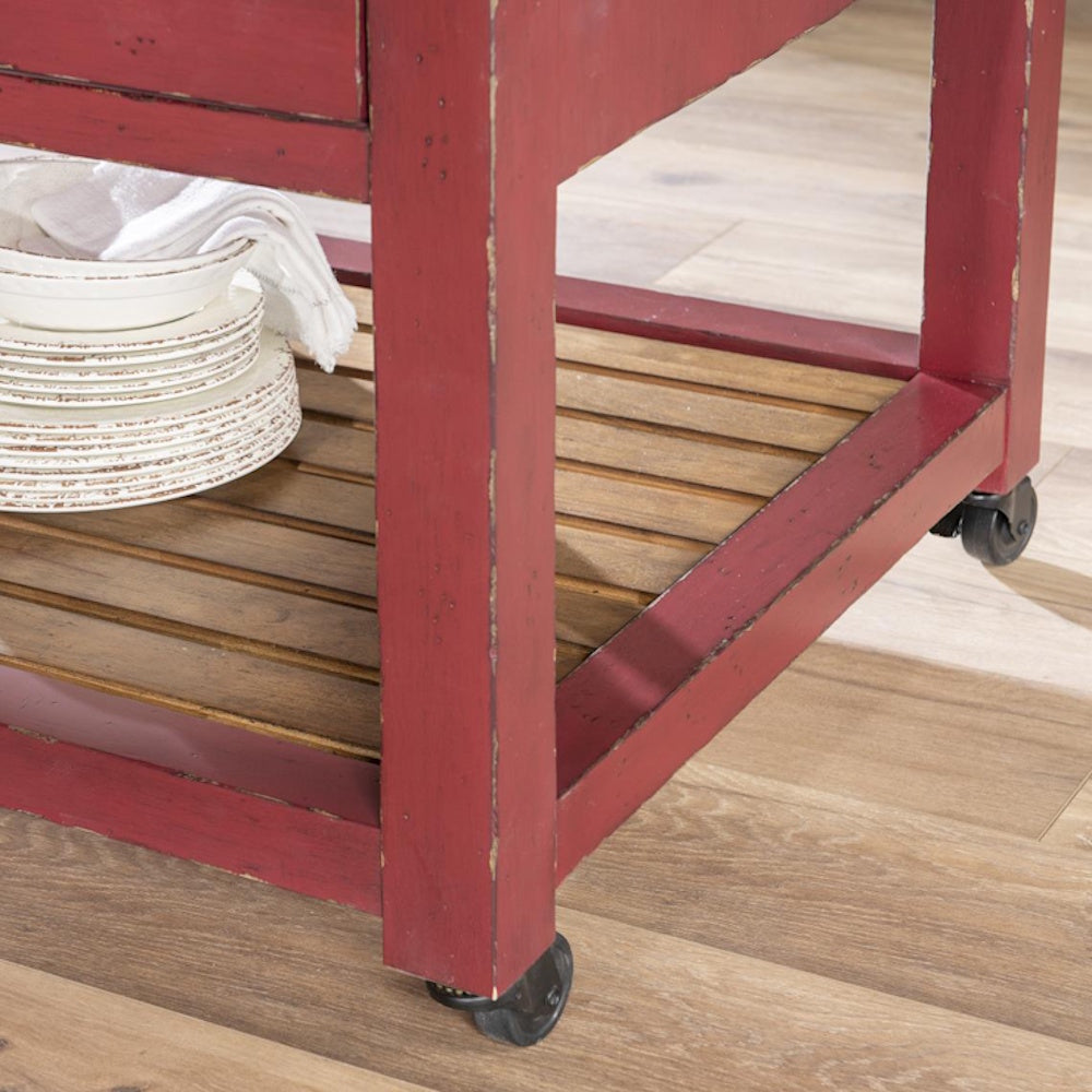 Rustic red kitchen island on wheels with slatted wood shelf and white ceramic dishes.