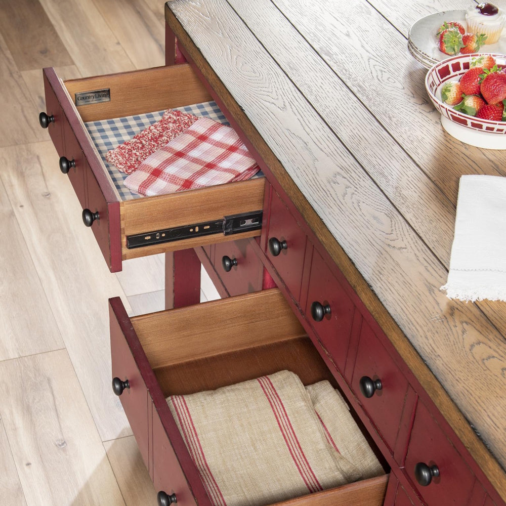 Red farmhouse kitchen island with open wood drawers, oak countertop, and storage for linens.