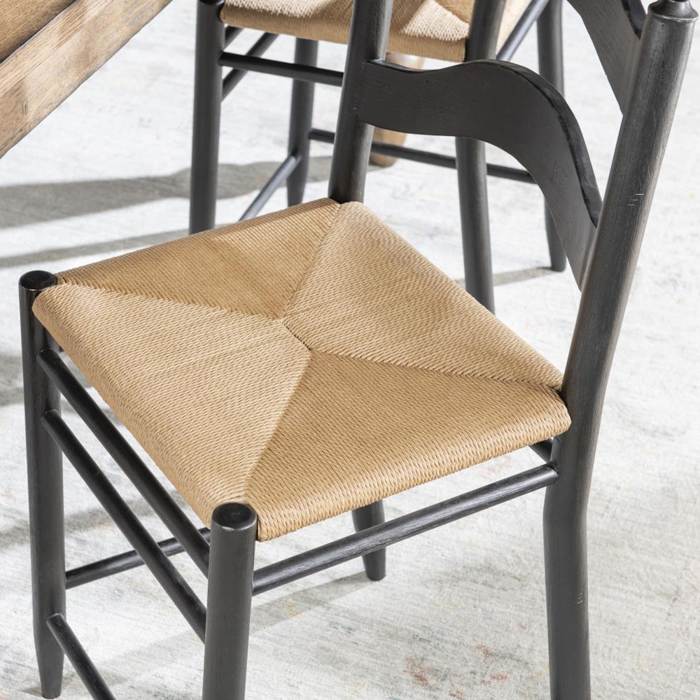 Close-up of gray ladder-back chair with handwoven natural rush seat and dark wood frame.