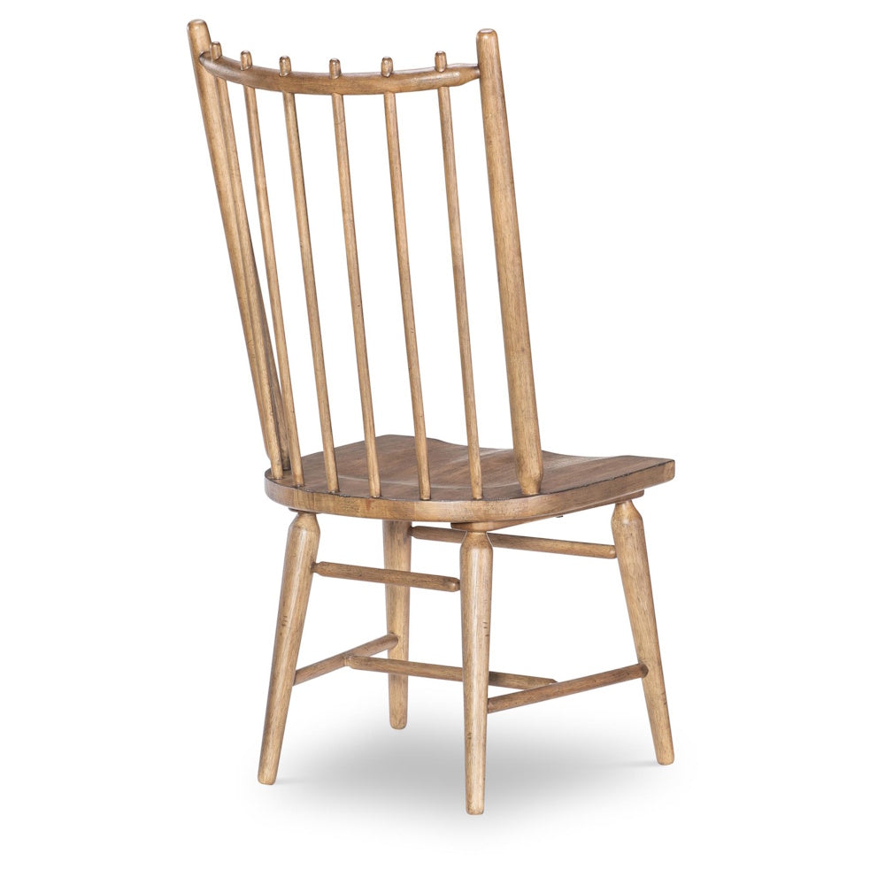 Rear view of a light-brown wooden spindle-back chair on a white background.
