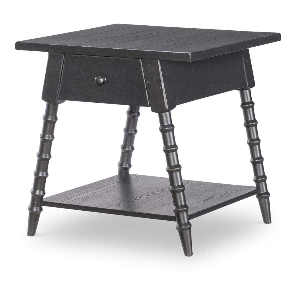 Black wood end table with one drawer, bobbin style legs, lower shelf, and plank top.