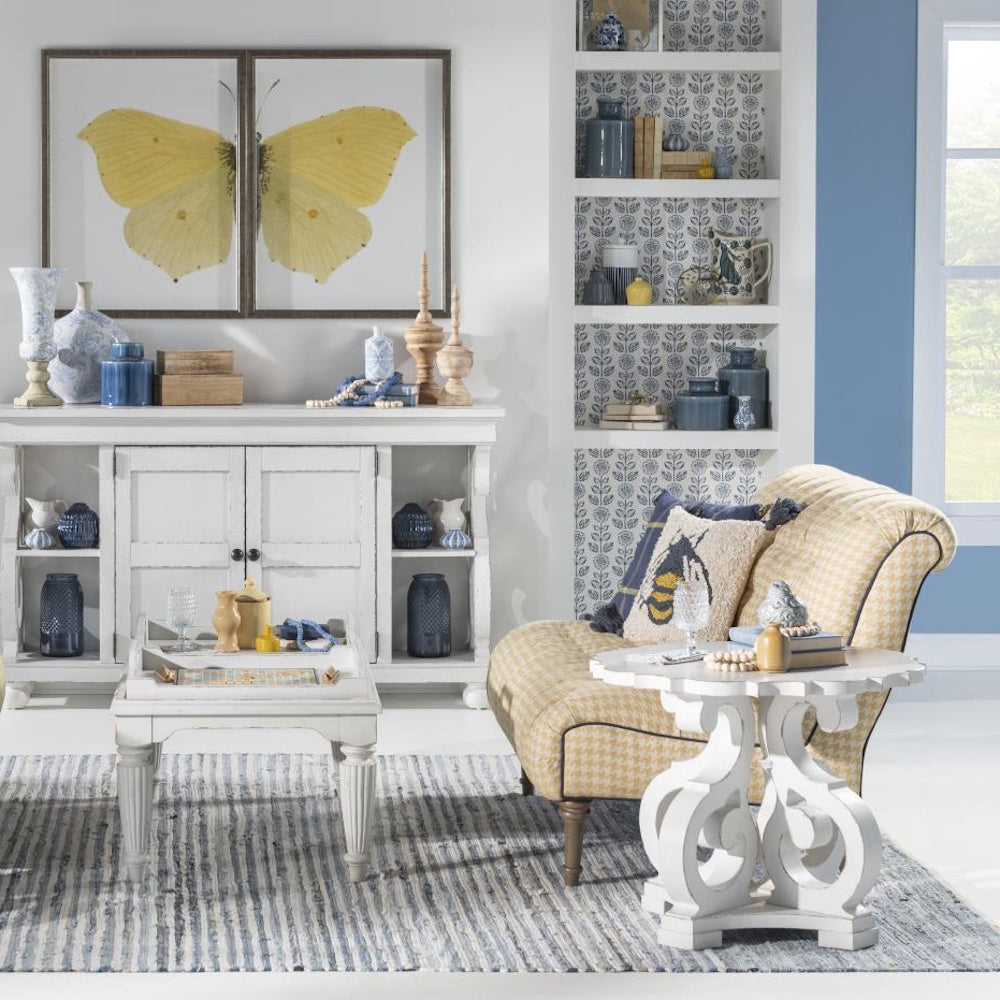 Cozy living room with yellow armchair, white tables, and butterfly wall art in a blue and white theme.
