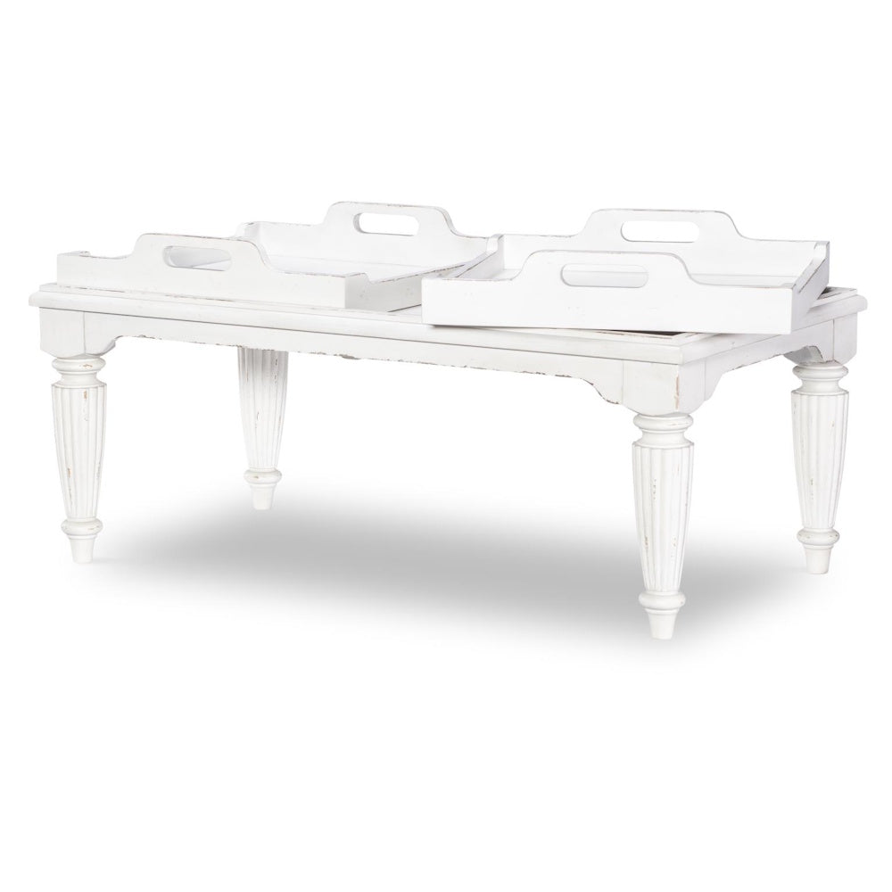 Distressed white wooden coffee table with three removable tray tops and turned legs.