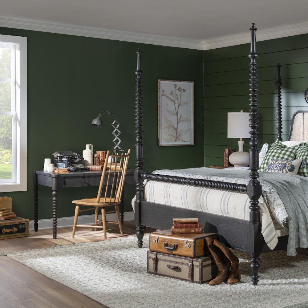 Rustic green bedroom with a black poster bed and a vintage writing desk featuring bobbin legs.
