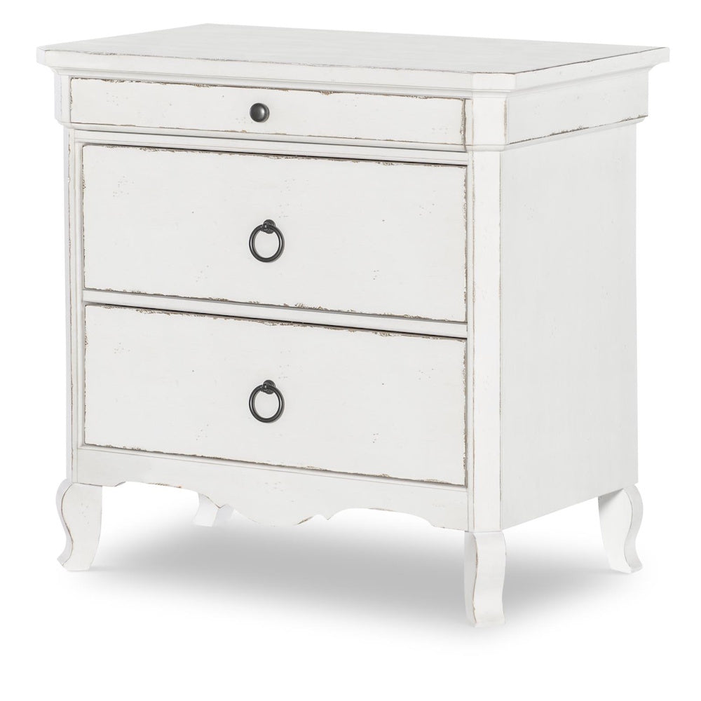 White distressed wood nightstand with three drawers and black ring pulls.