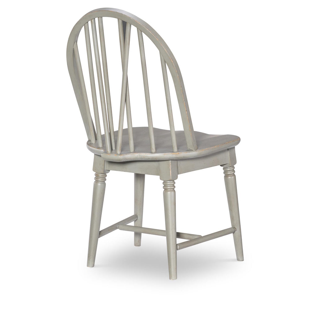 Rear view of a light gray Windsor side chair with a curved spindle back and tapered wooden legs.