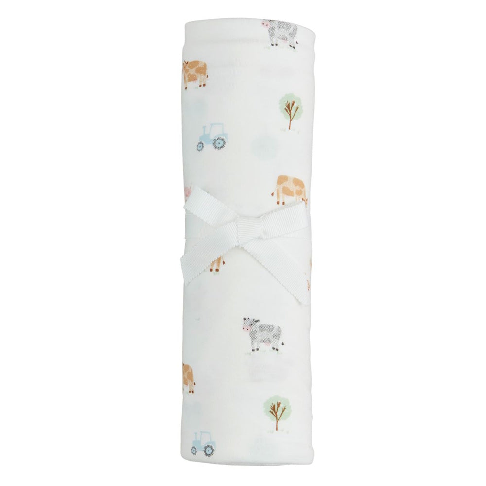 Rolled white soft knit baby swaddle with farm print featuring cows, tractors, and trees, tied with a white ribbon bow.