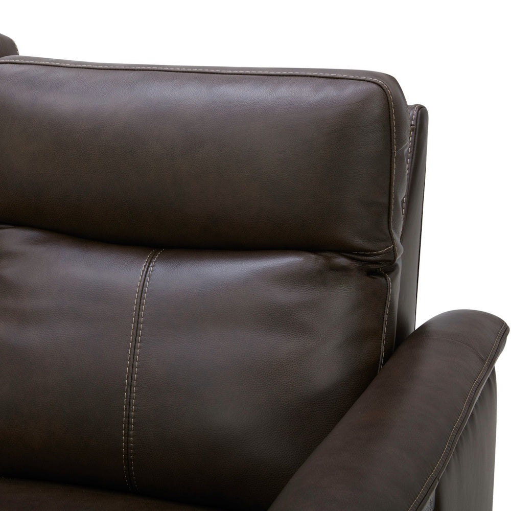 Close-up of a brown leather recliner with white contrast stitching and padded headrest.