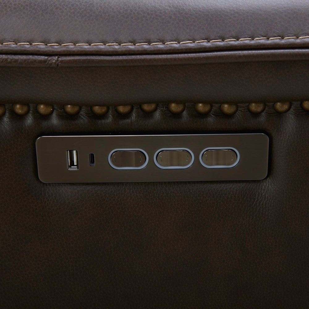 Brown leather power recliner control panel with USB charging ports and brass nailhead trim.