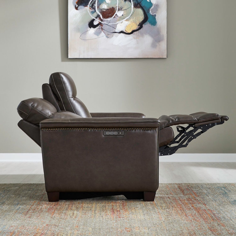 Modern brown leather power recliner chair with nailhead trim in a living room.