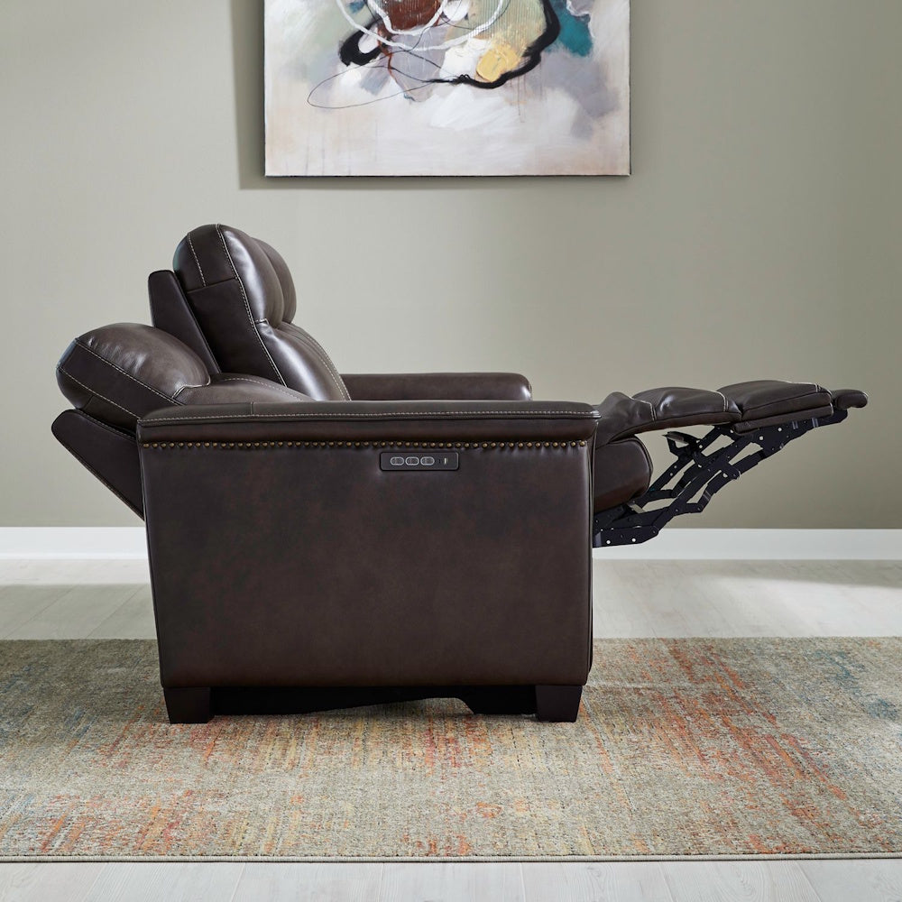 Dark brown leather power recliner chair with nailhead trim and extended footrest in a living room.