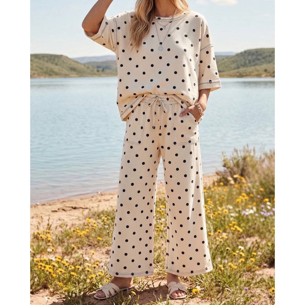 Woman wearing a cream and black polka dot short-sleeve top and matching wide-leg drawstring pants.