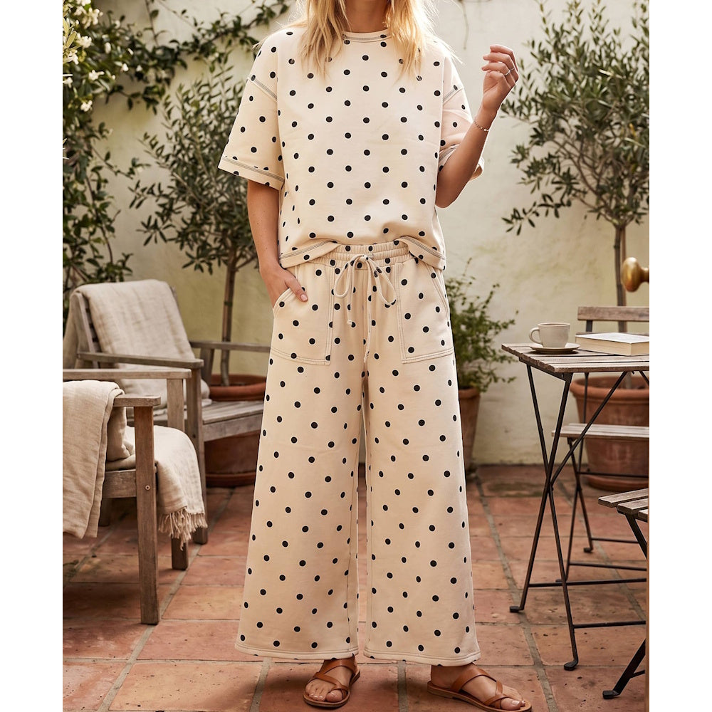 Woman wearing a cream short-sleeved top and matching wide-leg pants set with a black polka dot pattern.