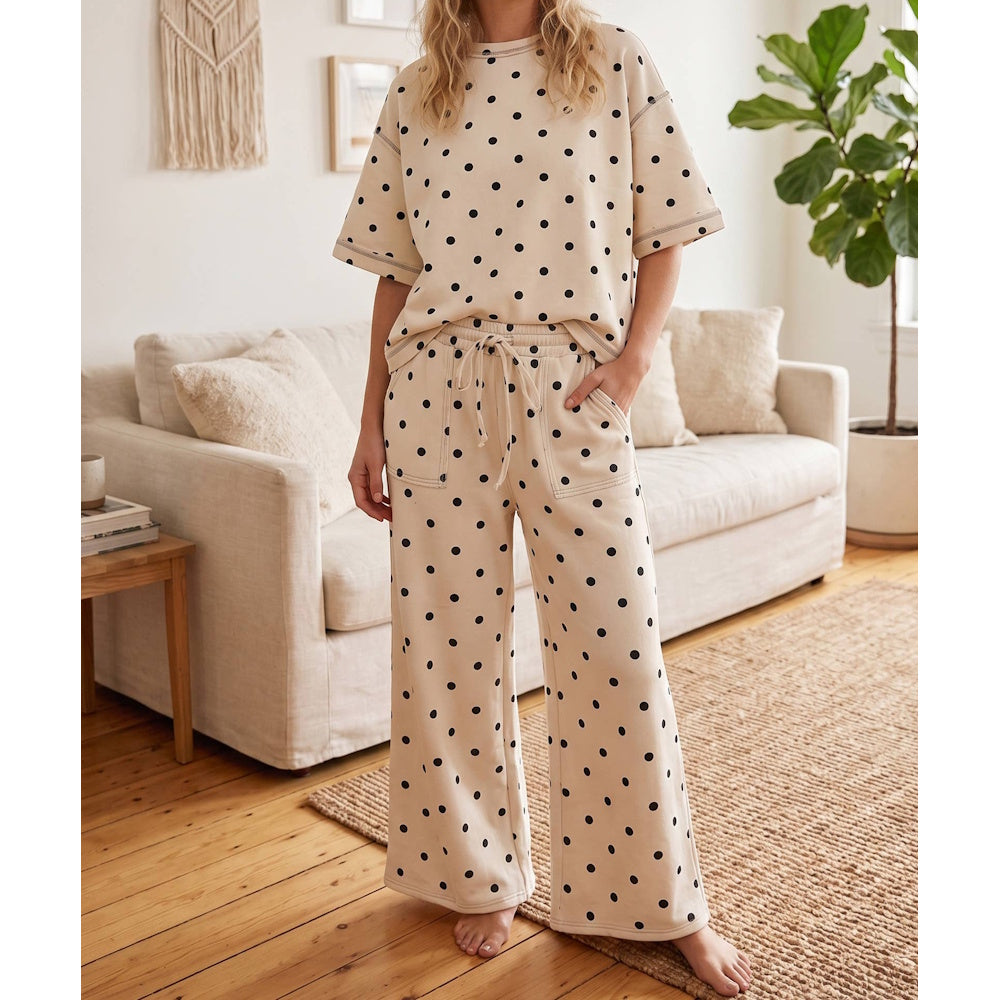 Woman wearing a matching cream and black polka dot short-sleeve top and wide-leg pants set.
