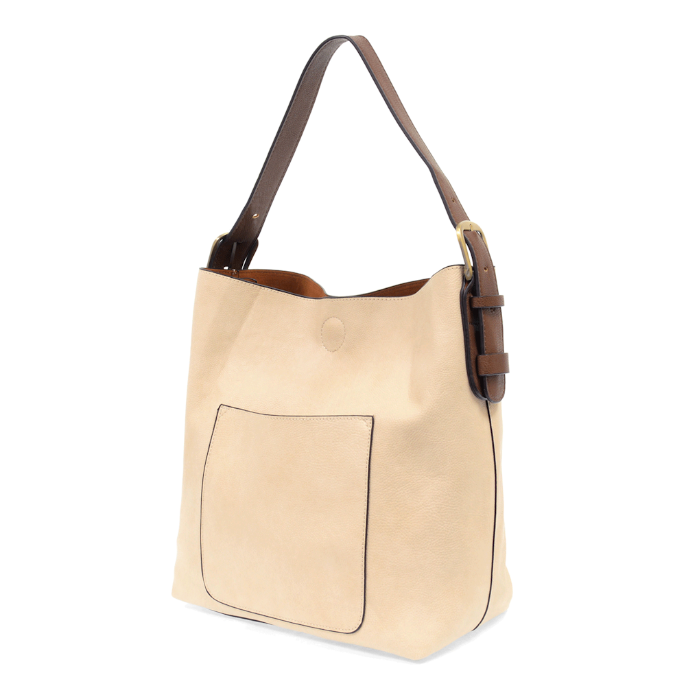 Cream hobo handbag with coffee brown shoulder strap and front slip pocket on a white background.