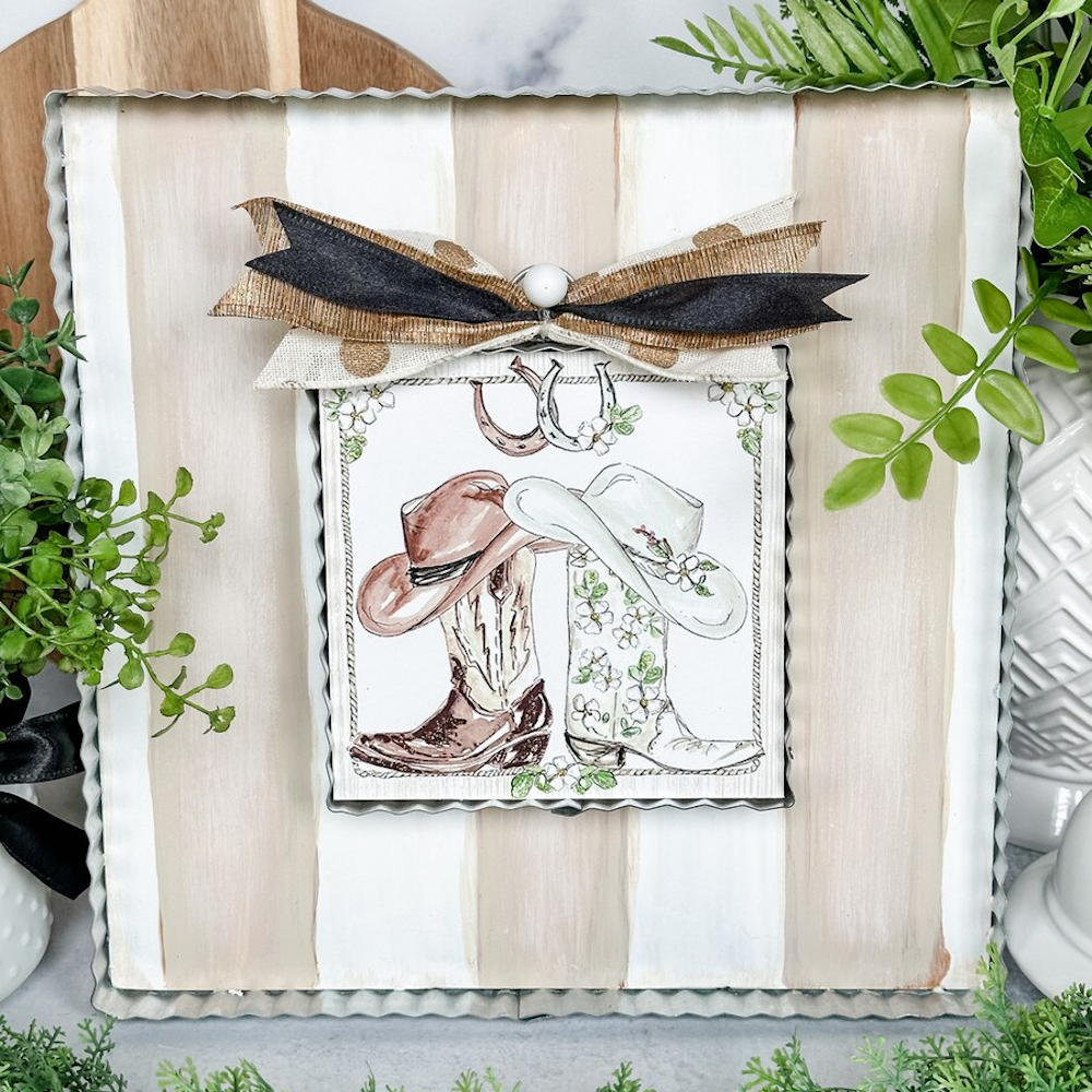 Rustic western decor featuring watercolor cowboy boots and hats on a striped corrugated metal display board.