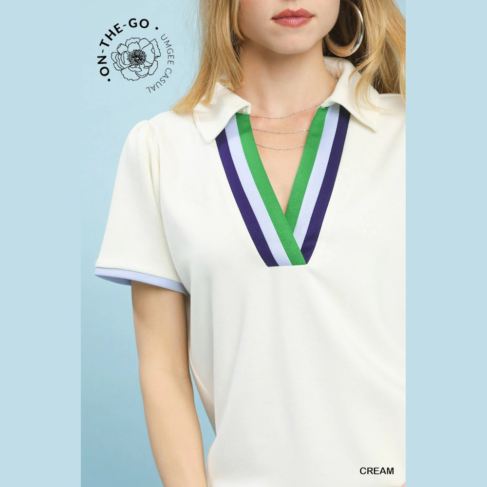 Cream V-neck polo with green, blue, and navy striped trim and short puff sleeves.