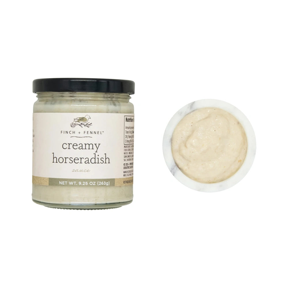 Jar of Finch + Fennel creamy horseradish sauce next to a small marble bowl filled with the sauce.