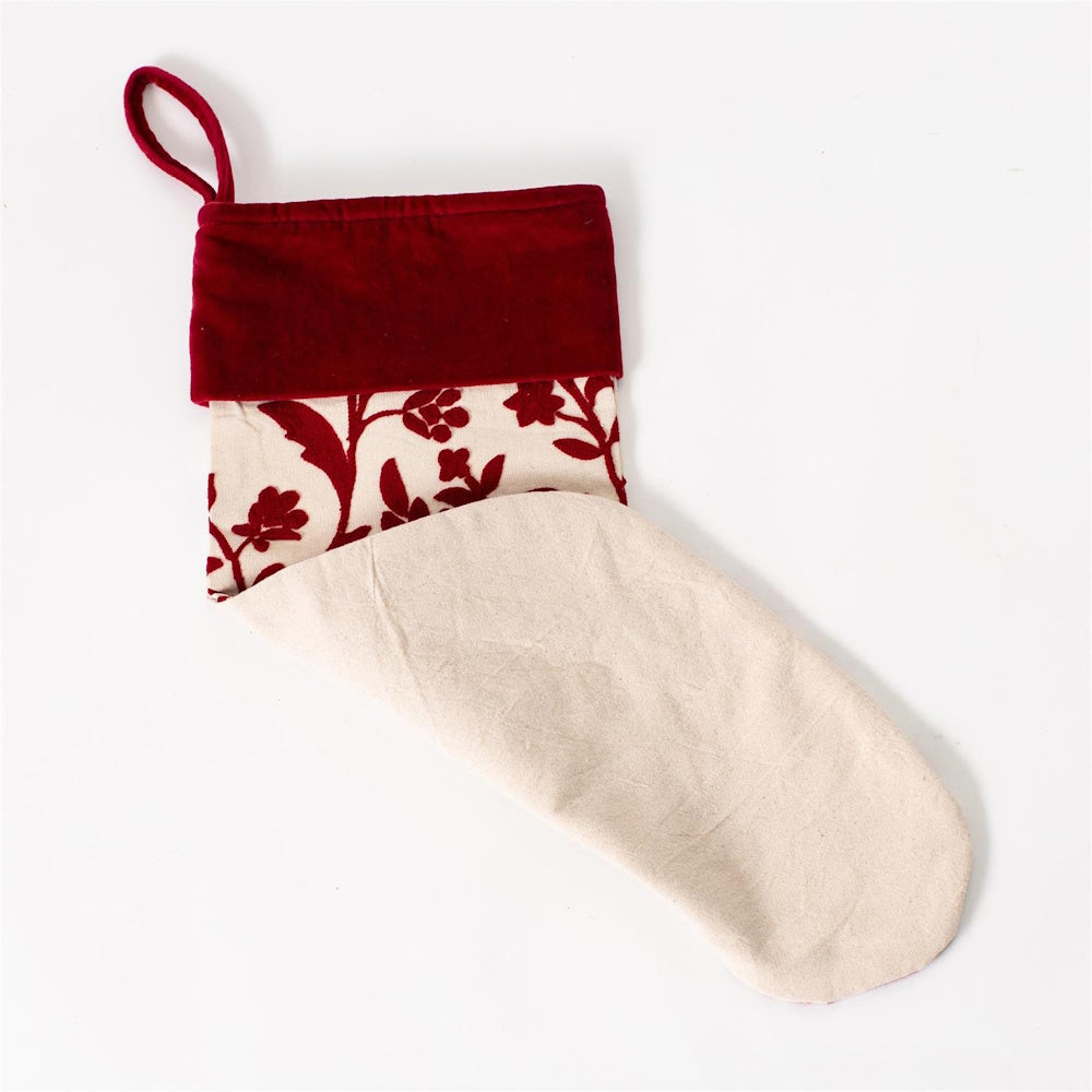 Folded Christmas stocking with a red velvet cuff and embroidered floral pattern on a white background.