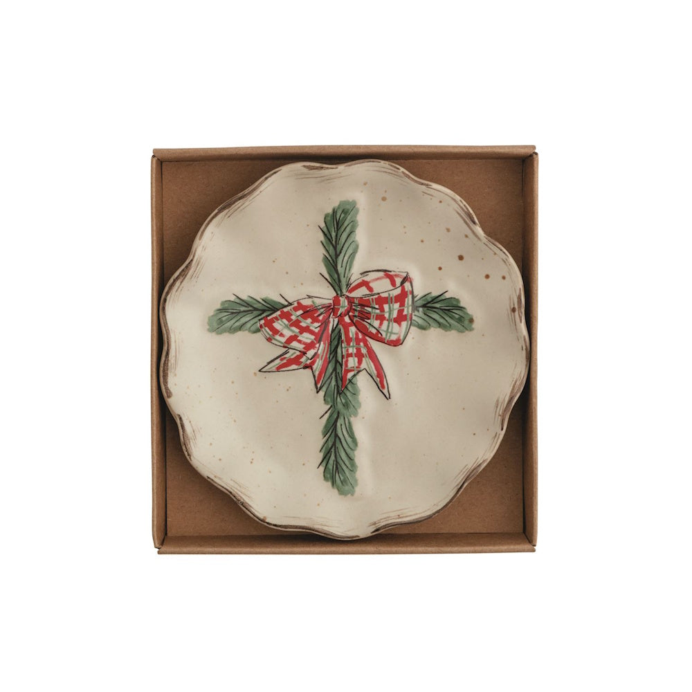 Round ceramic tidbit plate in a gift box with a cross design made of pine boughs and a red plaid bow.
