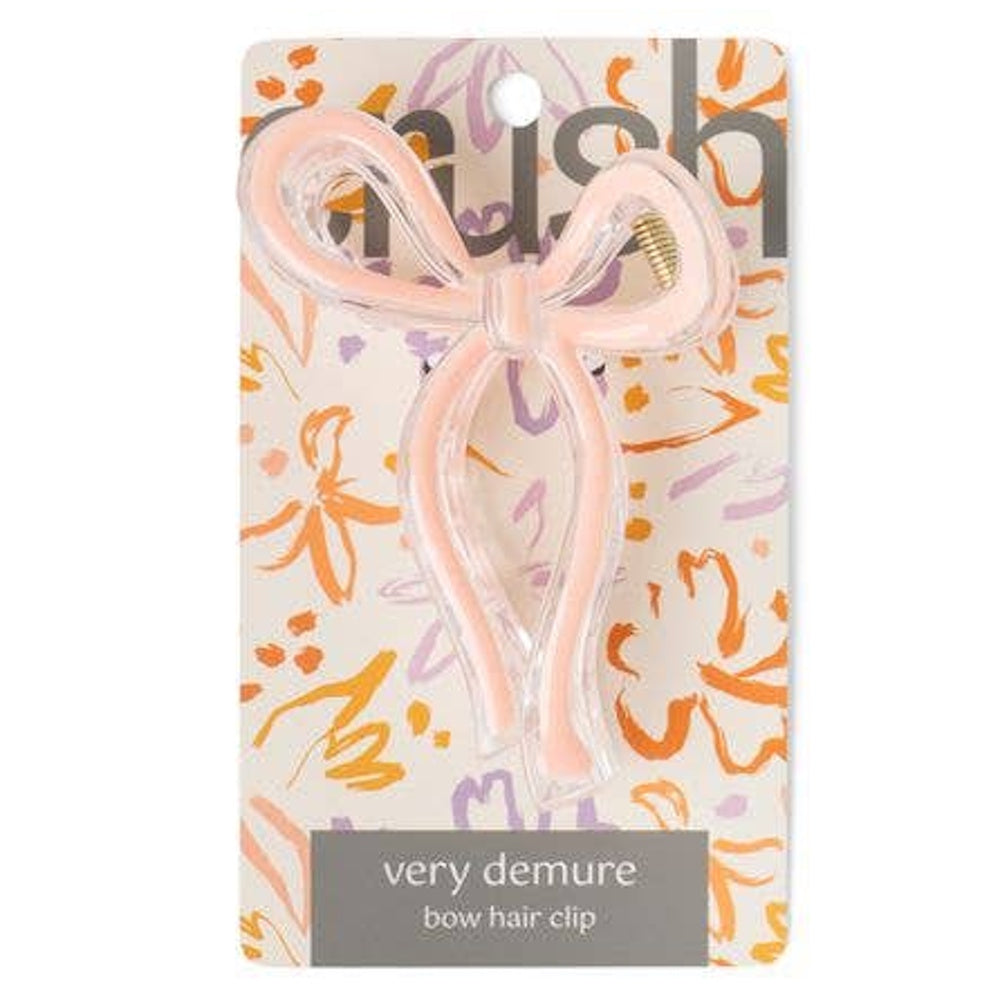 Light pink translucent bow hair clip on floral "very demure" product packaging.