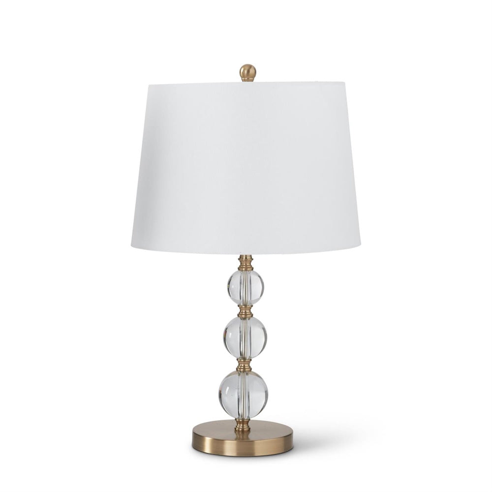 Elegant table lamp with stacked glass spheres, brass finish base, and a white tapered drum fabric shade.