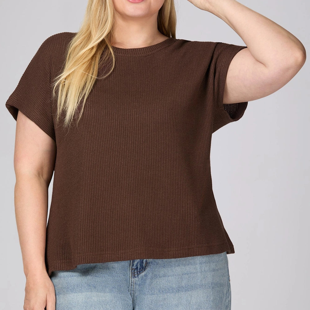 Plus-size woman wearing a brown waffle-knit drop-shoulder short-sleeve top with blue jeans.