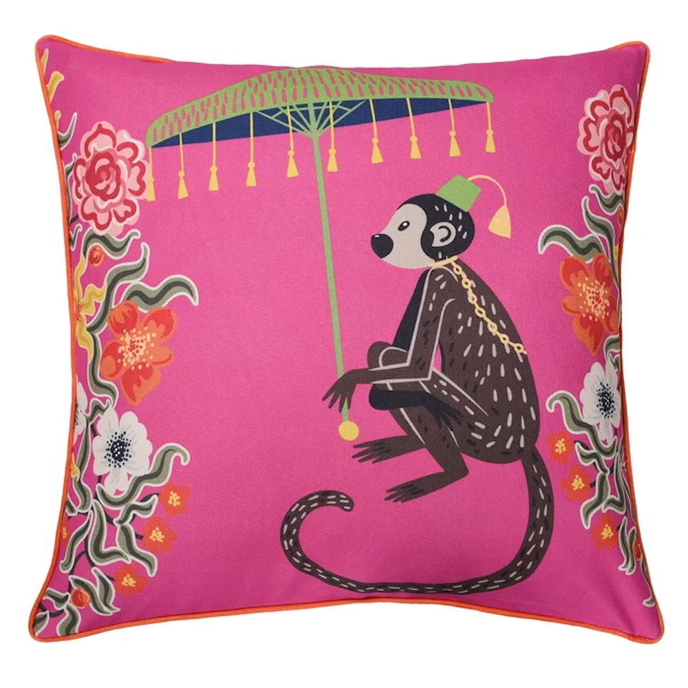 Pink decorative pillow featuring a monkey holding a green umbrella, surrounded by colorful floral patterns.