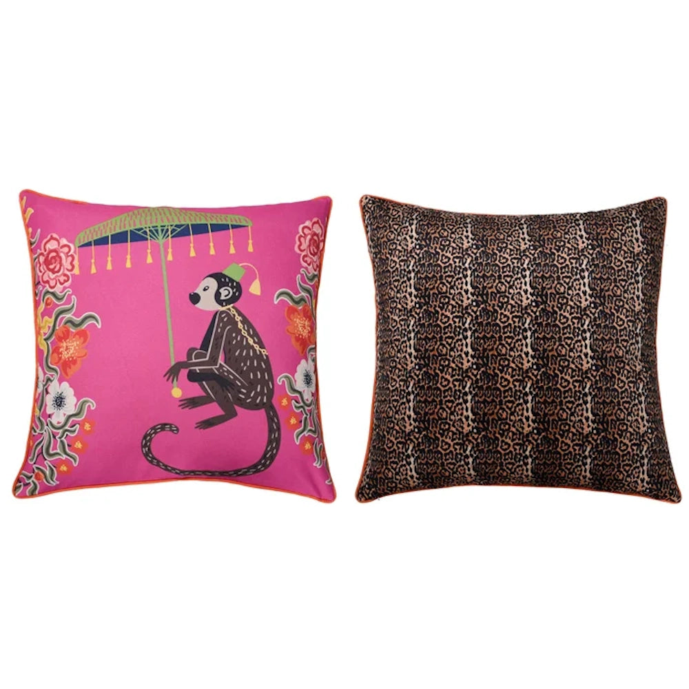 Pink pillow with monkey and umbrella next to a brown leopard print decorative cushion.