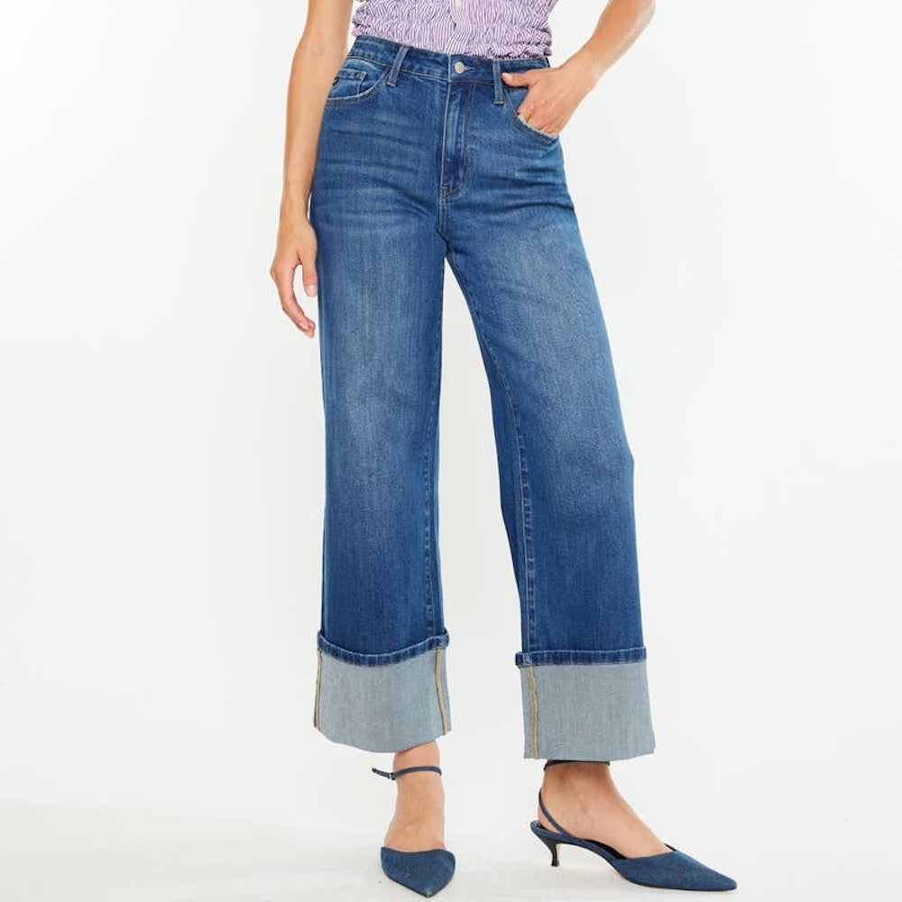 Woman wearing high-rise wide-leg blue jeans with wide cuffed hems and pointed blue kitten heels.