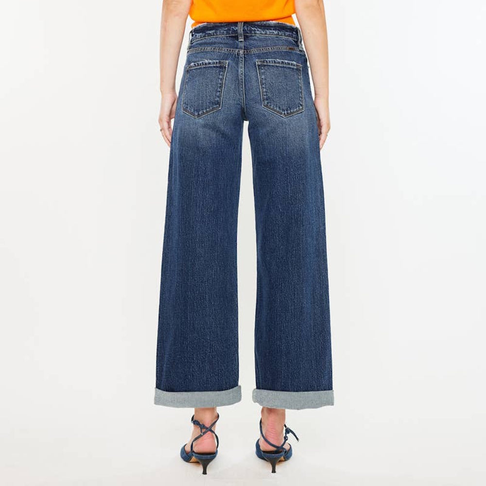 Back view of dark-wash high-rise wide-leg jeans with back pockets and large cuffed hems, paired with blue heels.