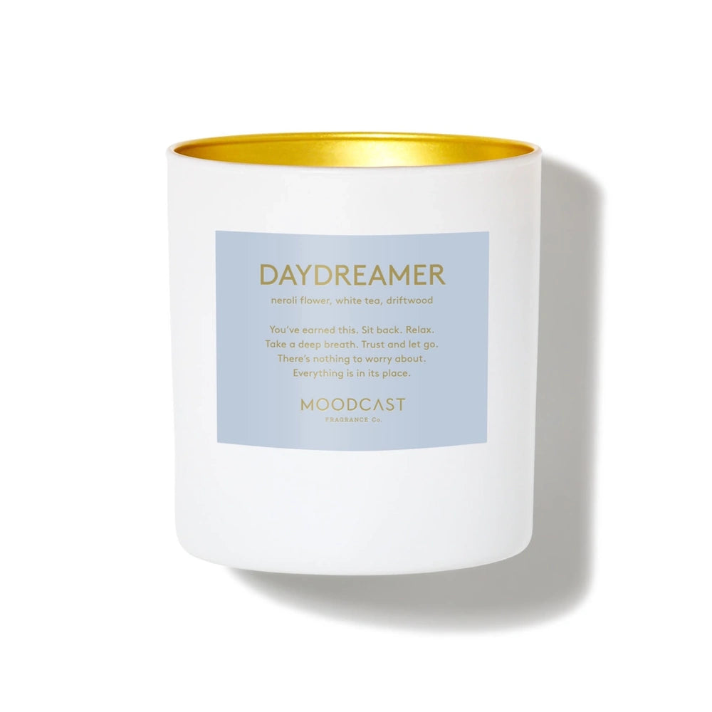 White jar candle with a light blue Moodcast "Daydreamer" label and a gold interior rim.