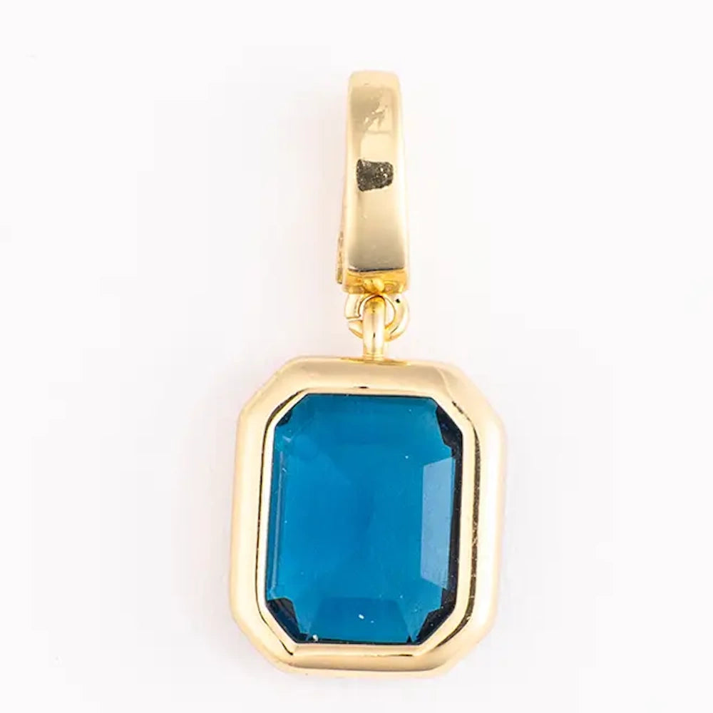 Gold charm featuring a rectangular emerald-cut blue gemstone set in a thick gold frame.