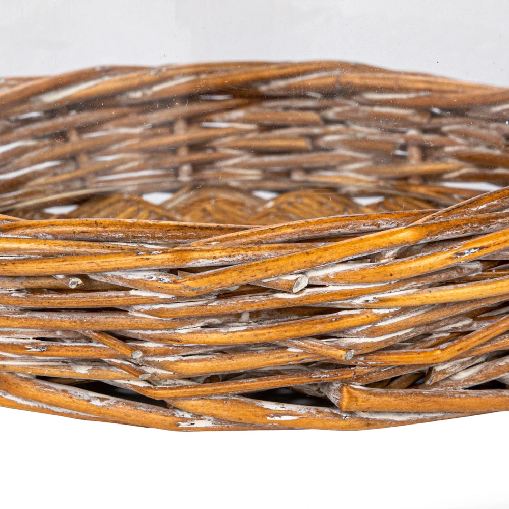 Close-up of a rustic, woven brown willow basket base with whitewashed accents and a glass cloche rim.