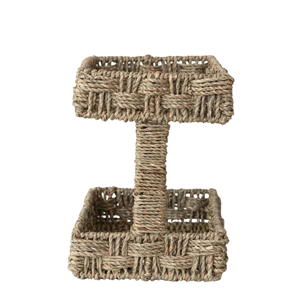 Side profile view of an empty two-tier hand-woven seagrass basket tray on a white background.