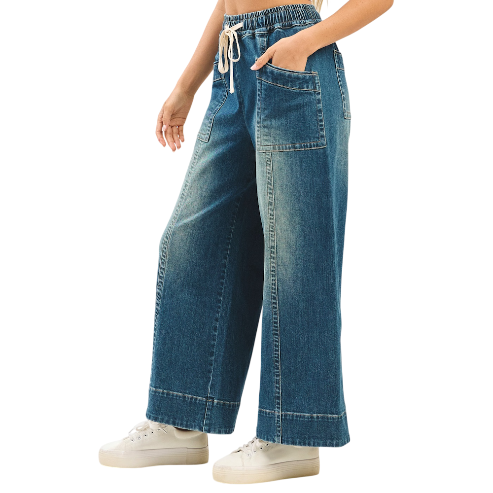 Side view of faded wide-leg denim pants with elastic drawstring waist and oversized patch pockets.