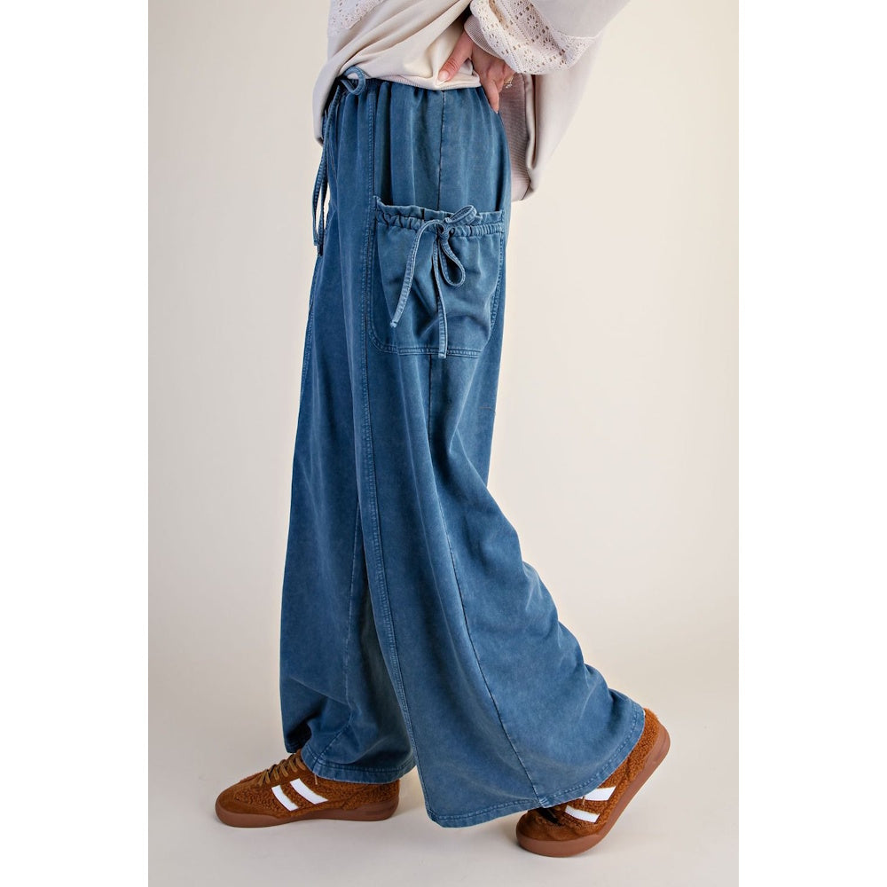 Side view of blue denim washed terry knit wide-leg pants with tie-accent cargo pockets.