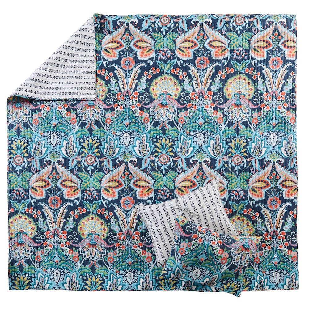 Colorful botanical paisley quilt with matching pillow sham and accent pillow on a blue background.