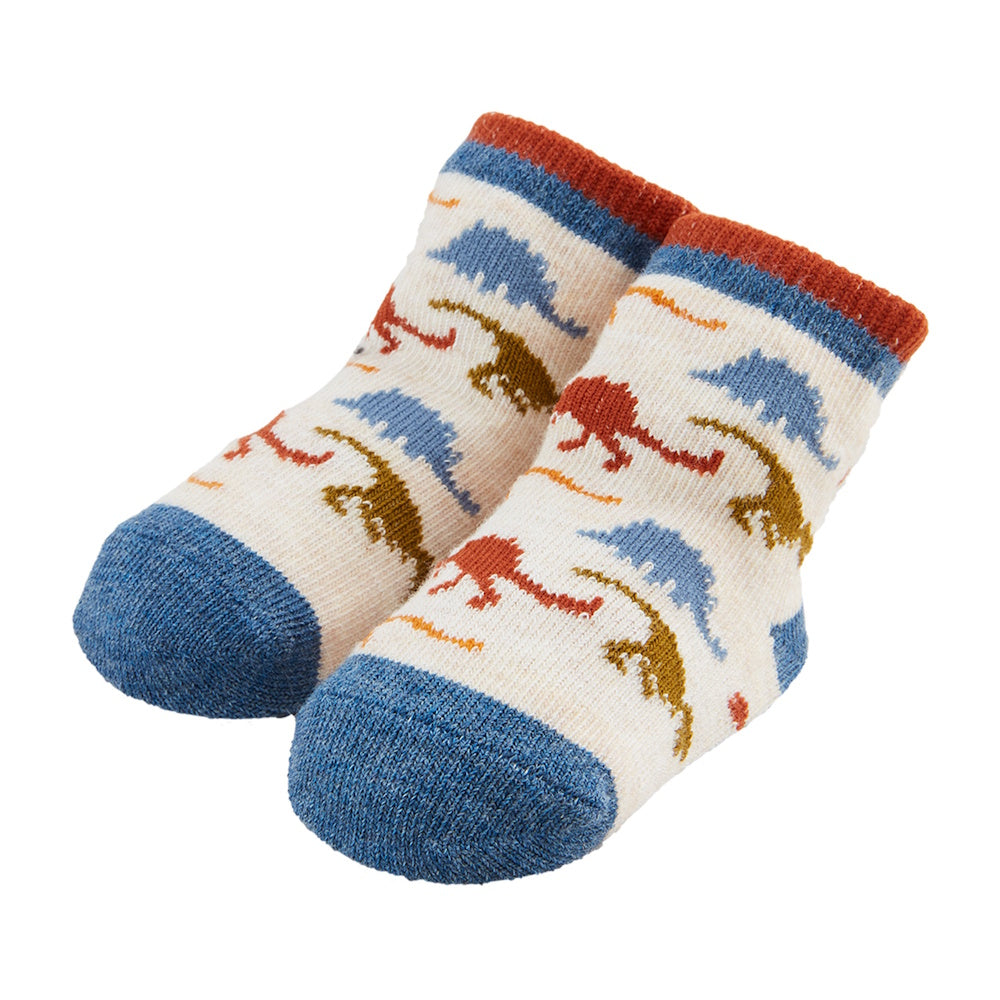 Pair of cream-colored baby socks with blue, orange, and green dinosaur patterns, blue toes, and orange ribbed cuffs.