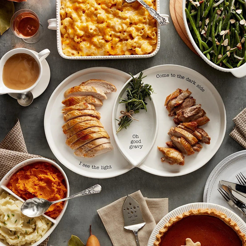 Divided Thanksgiving platter with light and dark turkey meat surrounded by holiday side dishes.
