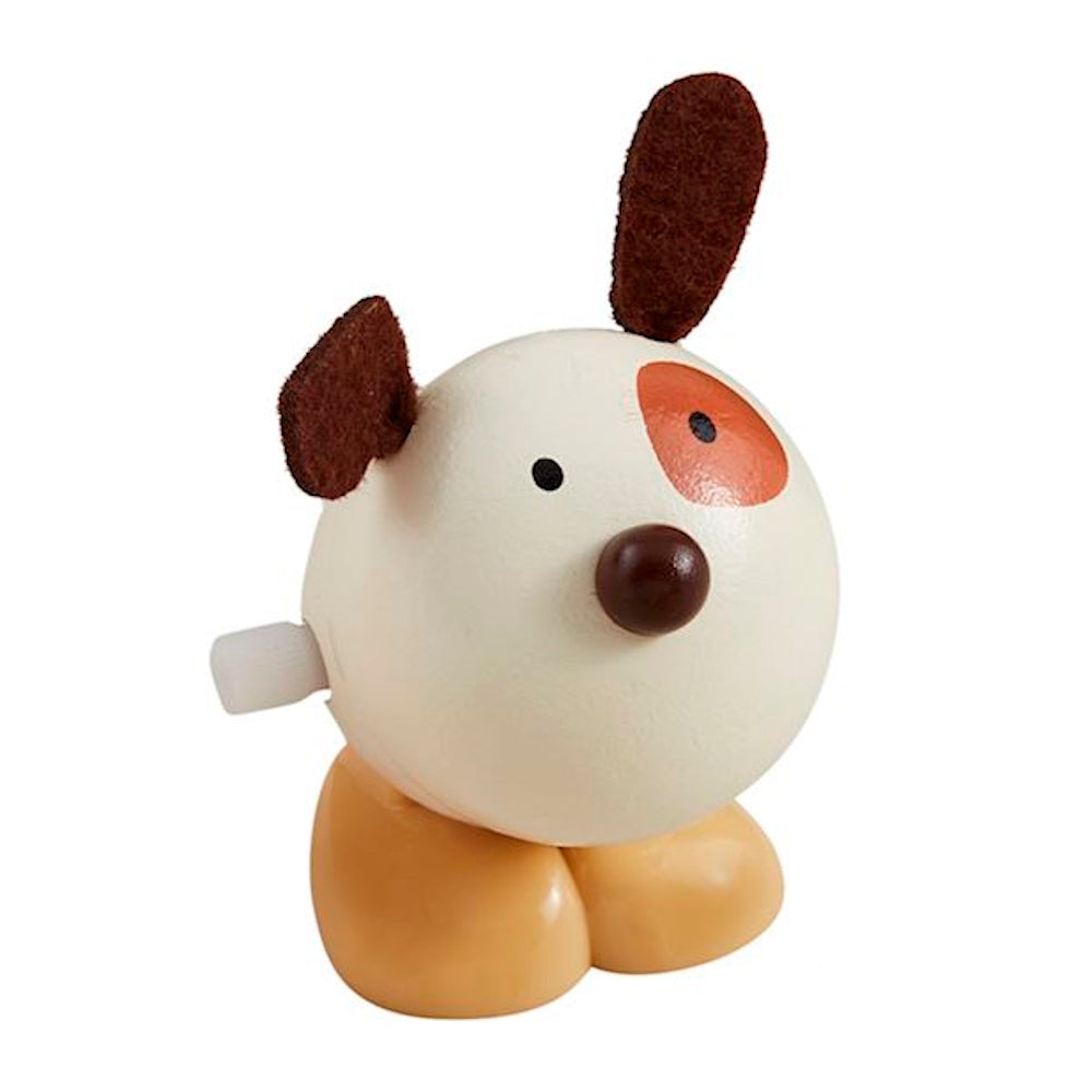 Wooden wind-up dog toy with a round white head, brown felt ears, orange eye patch, and tan legs on a white background.