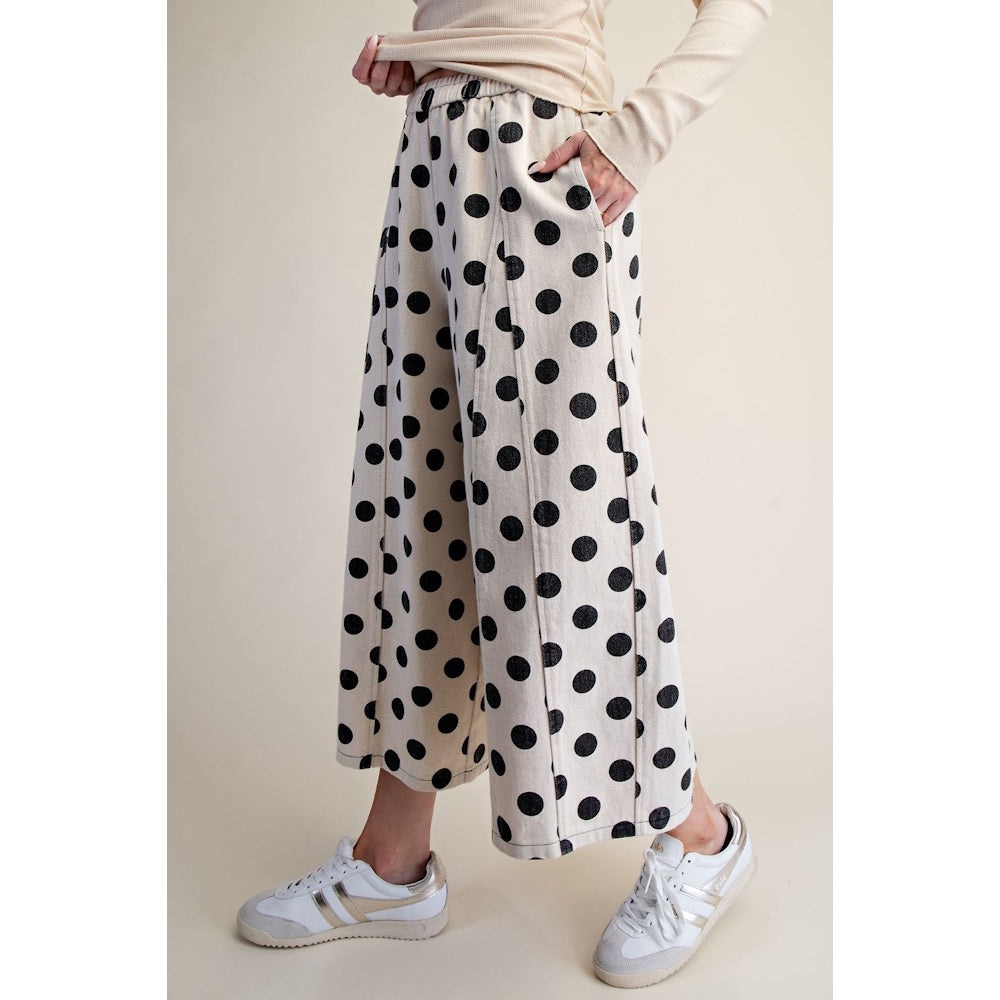 Side view of white wide-leg pants with a black polka dot print and sneakers.