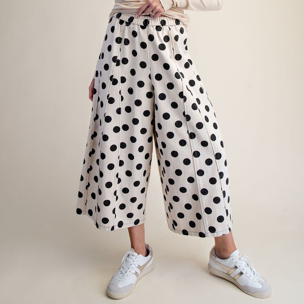 White wide-leg pants with a black polka dot print paired with sneakers.