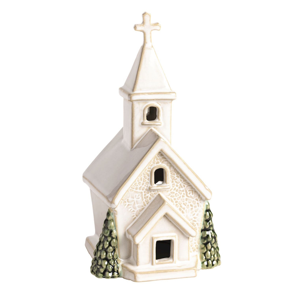 White ceramic church figurine with pressed lace texture, cross steeple, and green evergreen trees.