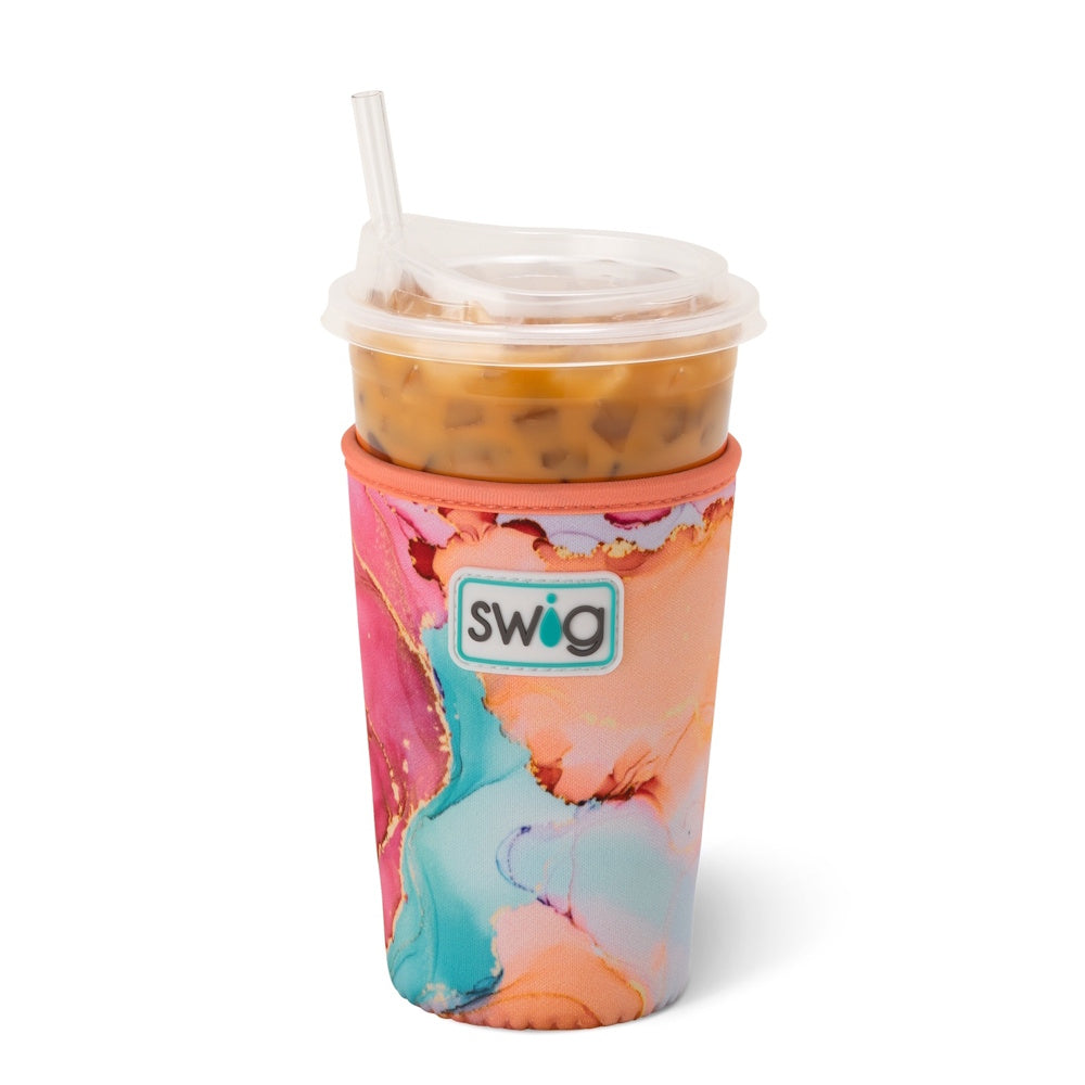 A plastic cup of iced coffee with a straw, wrapped in a colorful pink, orange, and blue Swig sleeve.