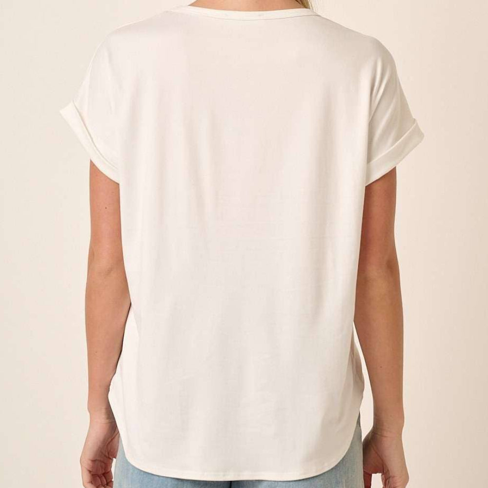 Back view of a woman wearing a white round neck dolman short sleeve knit top with cuffed sleeves.